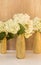 Golden glittered bottles with hydrangea flowers. White flowers in gold vases