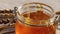 Golden honey pours into glass container, production organic or natural foods