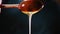 Golden honey from wooden spoon pours slow motion closeup