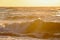 Golden illuminated sea waves with the setting sun in the background