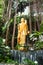 Golden image of Buddha is standing in a bush