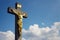 Golden Jesus Christ crucifixion statue, sunny summer day blue sky background