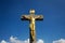 Golden Jesus Christ crucifixion statue, sunny summer day blue sky background