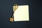 A golden key on a piece of note paper. Wish list, problem solution, idea, decoding, business concept on a black background with a