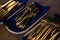 Golden knives spoons and forks in wooden tray on table