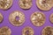 Golden lemon slices on purple background, flat lay