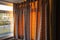 Golden light of a sunset glowing through hanging curtains on one side of a bay window