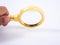 Golden magnifying glass in hand on white background