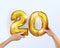 Golden metal balloon number twenty 20. party decoration with Golden balloons. The number 20 is in your hand.Anniversary sign for a
