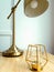 Golden metal lamp stands on a wooden table next to a candlestick