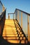 Golden metal stairs towards the roof under blue sky