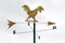 Golden metal weathervane over the white sky background.