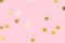 golden metallic star confetti on a pastel pink background