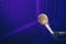 Golden microphone on stand, purple background with acoustic foam in studio