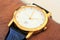 Golden modern wrist watch showing time as 2pm