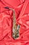 Golden musical instrument alto saxophone on red cloth top view