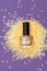Golden nail polish bottle on purple background. Golden nail polish bottle decorated with small glitter gold stars on purple