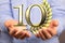 Golden number 10 and a spike of wheat over someone\'s hands