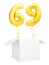 Golden number sixty nine inflatable balloon with golden ribbon flying out of blank white box isolated on white