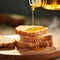 Golden olive oil being poured on toasted bread slice on wooden board