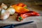 Golden onions and sweet organic pointed peppers with a kitchen knife on a wooden cutting board