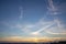 Golden orange sunset and deep blue sky with white feathery clouds contrasting