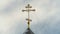 Golden Orthodox cross on a background of blue sky and fast clouds