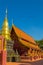 Golden pagoda and brown ubosot with blue sky background