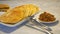 Golden pancakes and fried side dish on plates, knife and fork on marble table, snack