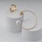 Golden pearl bracelet and three types of gold ring on white paper cylinders