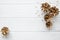 Golden pine cones and beige beads on white wooden table background, top view, copy space.