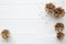 Golden pine cones and beige beads on white wooden table background, top view, copy space.