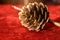 Golden pine cones on a red velvet as festive table ornament for Hanukkah or Christmas