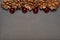 Golden pine cones and shiny red baubles border top of grey slate colour copy space