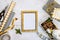 Golden ptoto frame, gift boxes, a crate full of pine cones and christmas toys and wrapping materials on a white wood old backgroun