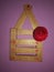 Golden and red colour mobile stand with beautiful red rose hanging on a pink wall by a nail