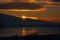 Golden reflections of the sun as sunset on the low tide of Pegwell Bay. The sun is moving behind a cloud and has sun rays