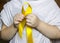 Golden ribbon in the hands of child. Concept: pediatric oncology, children`s cancer