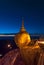 Golden Rock at twilight with praying people, KyaiKhtiyo pagoda