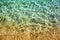 Golden sand under clear blue sea water and sunlight glow reflection close up top view, yellow sandy texture below ocean water