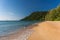 Golden sandy beach of tropical island with forested headland