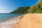 Golden sandy beach of tropical island with forested headland