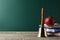 Golden school bell, apple and books on wooden table near green chalkboard. Space for text