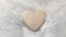 Golden sequin heart, top view on a white silky tulle background.