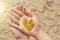 A golden shining heart lies in the hands of the girl. Heart in the palms. Golden heart