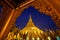 Golden Shwedagon Pagoda at night with twilight sky through the door frame