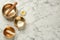 Golden singing bowls, mallets and flower on white marble table, flat lay. Space for text