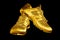 Golden sneakers black background isolated closeup, gold metal sport shoes, luxury running gumshoes, yellow metallic fitness boots