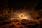 Golden sparks spray at night at stones rocks puddle reflects the sparks through glowing steel wool which is flung in a circle, Ger