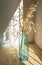 Golden spike plant on a blue glass bottle. Light and shadow contrast. Light pine table